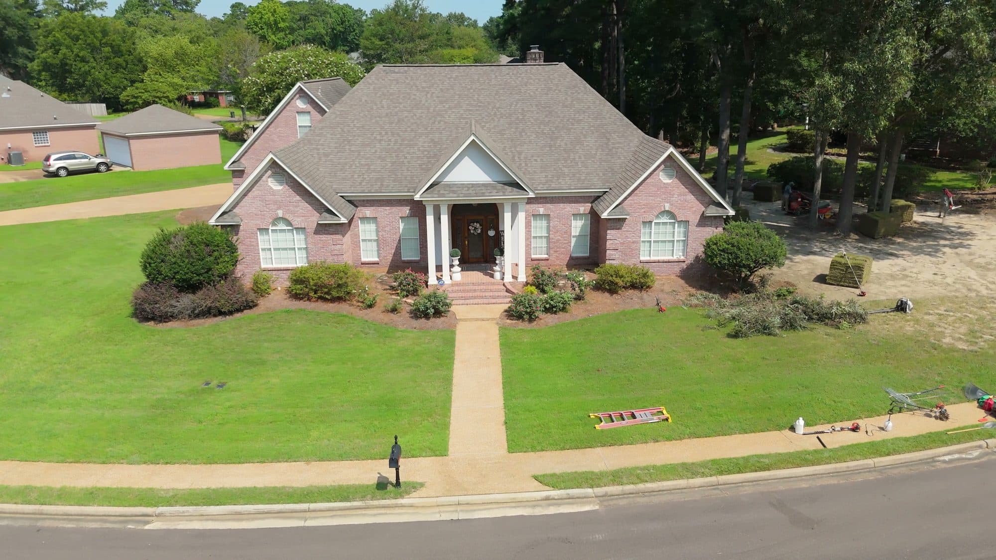 Aerial view of a brick home with a freshly maintained lawn and front beds