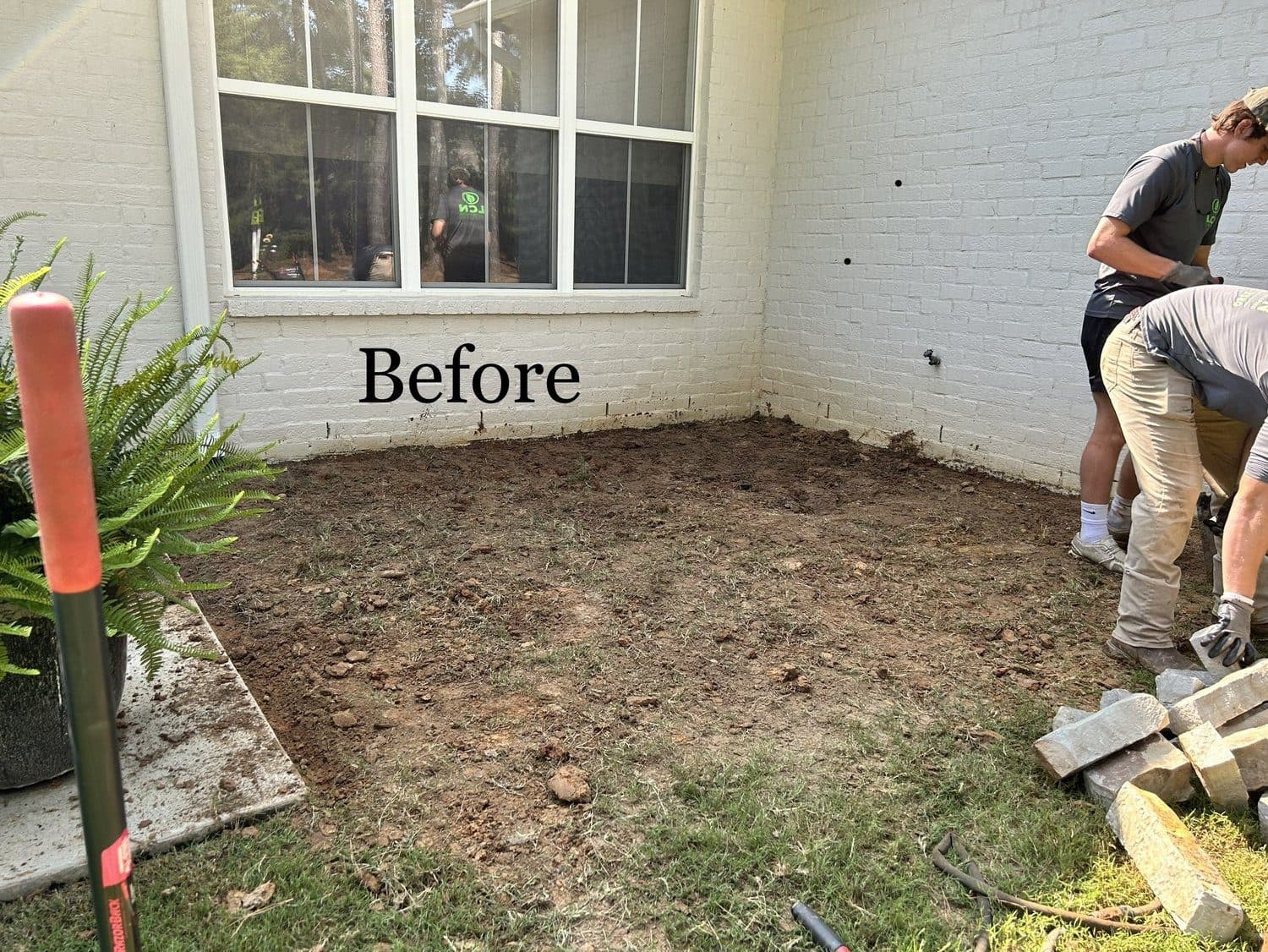 Before: bare dirt corner beside a brick wall