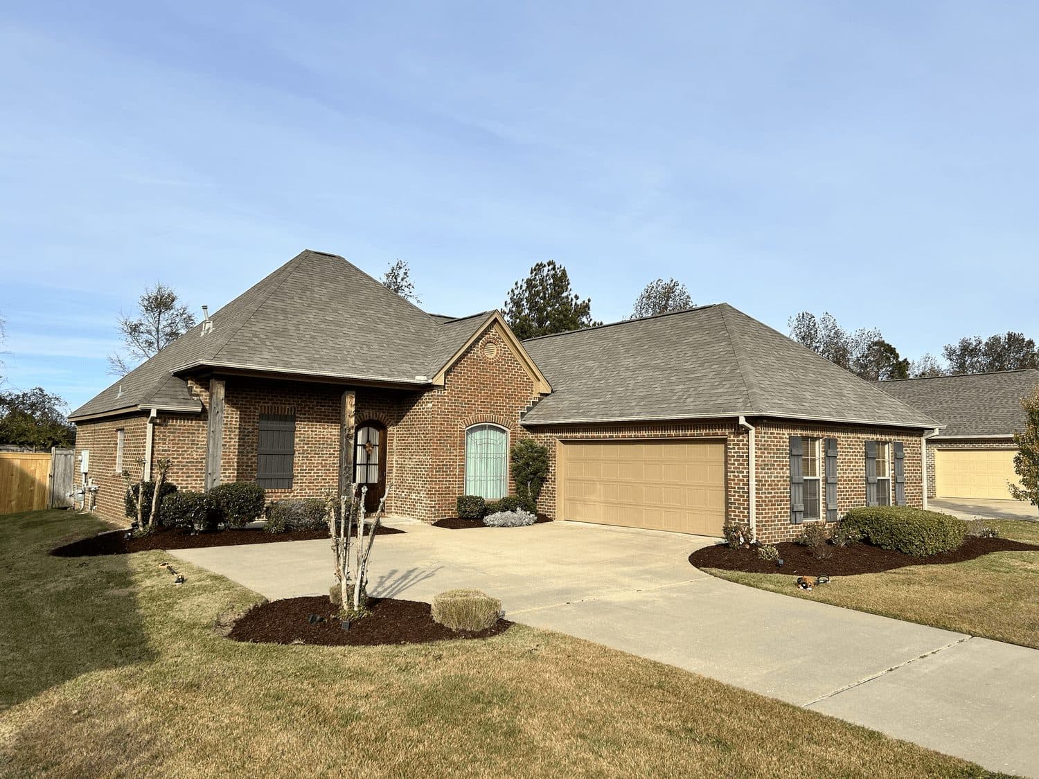 Pine straw beds and a crepe myrtle at a brick ranch home