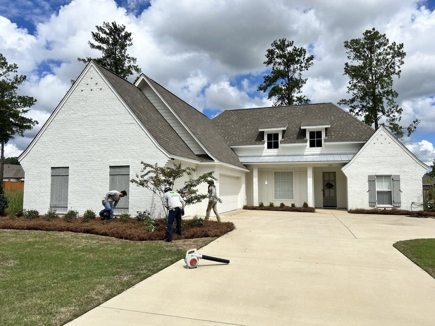 LCN crew installing new beds in front of a white brick home
