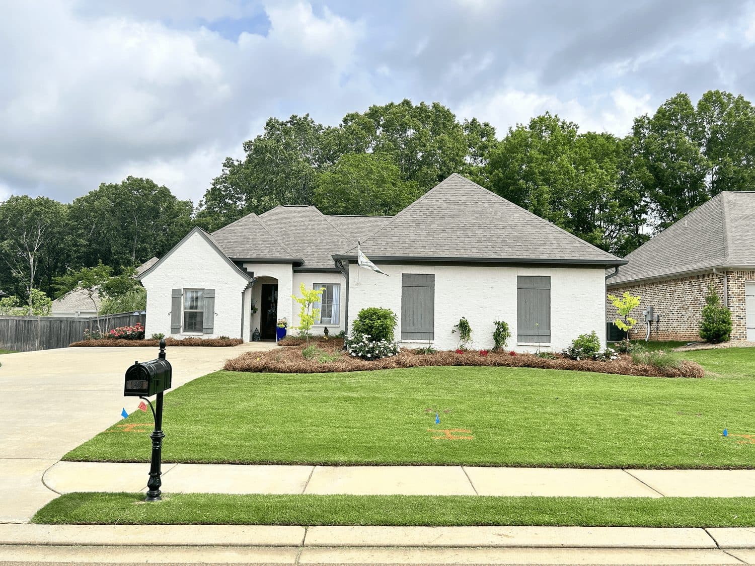 Edged lawn, mailbox and trimmed beds in front of a white home