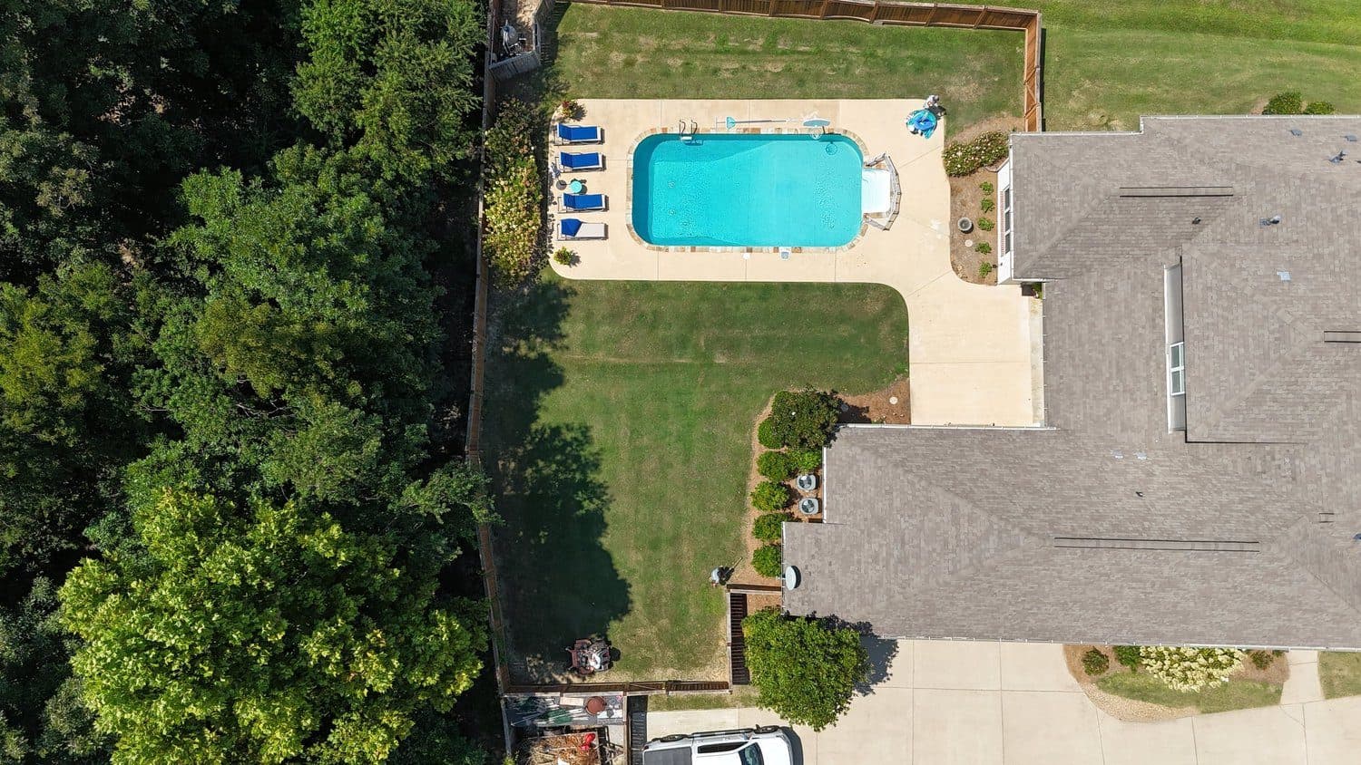 Top-down drone view of a backyard lawn beside a pool