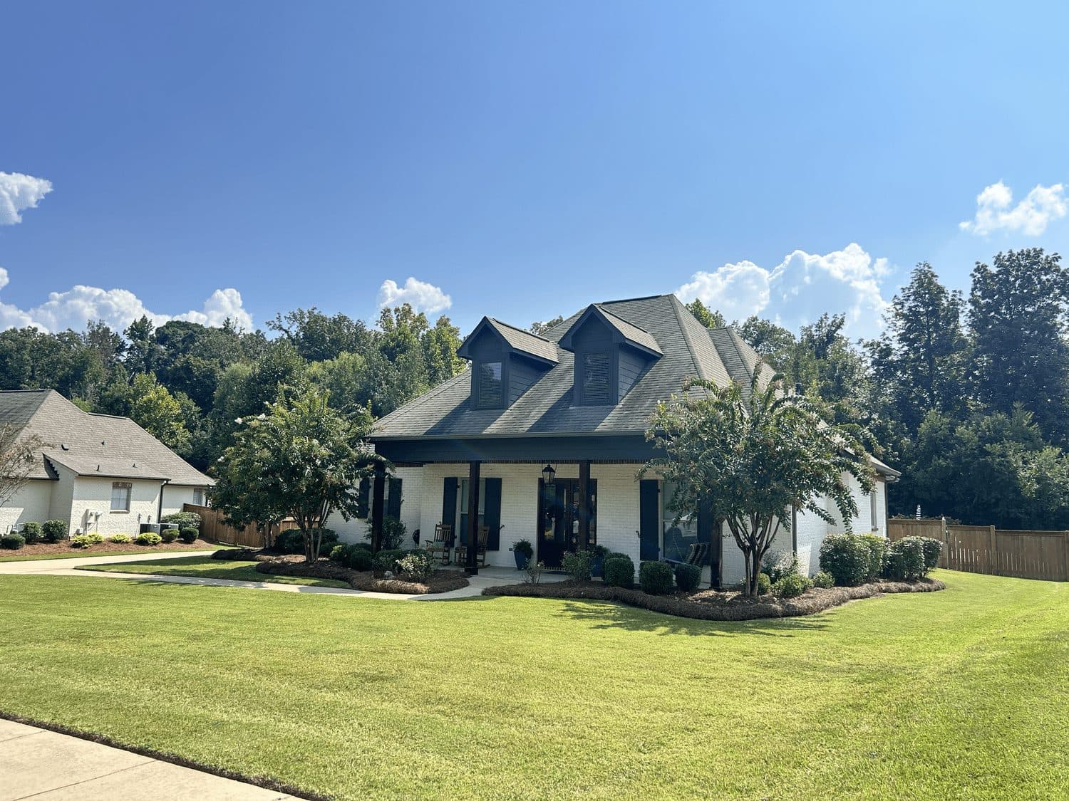Finished lawn and beds in front of a navy farmhouse-style home