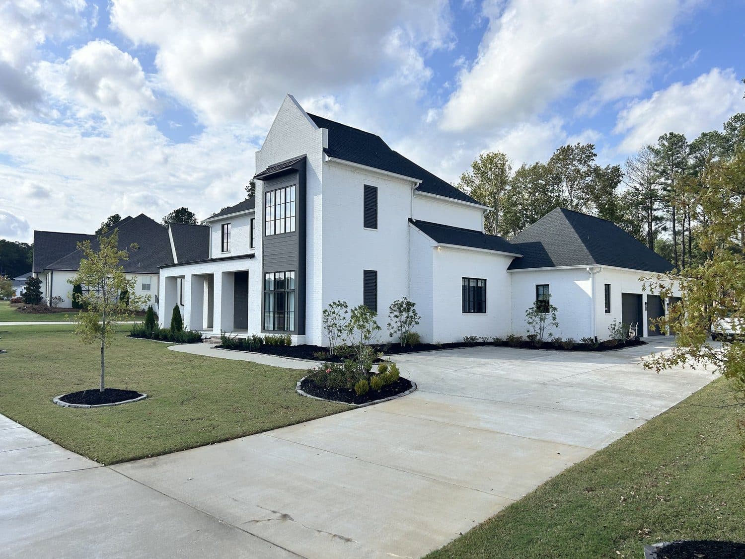 New sod, beds and a young tree at a modern white farmhouse