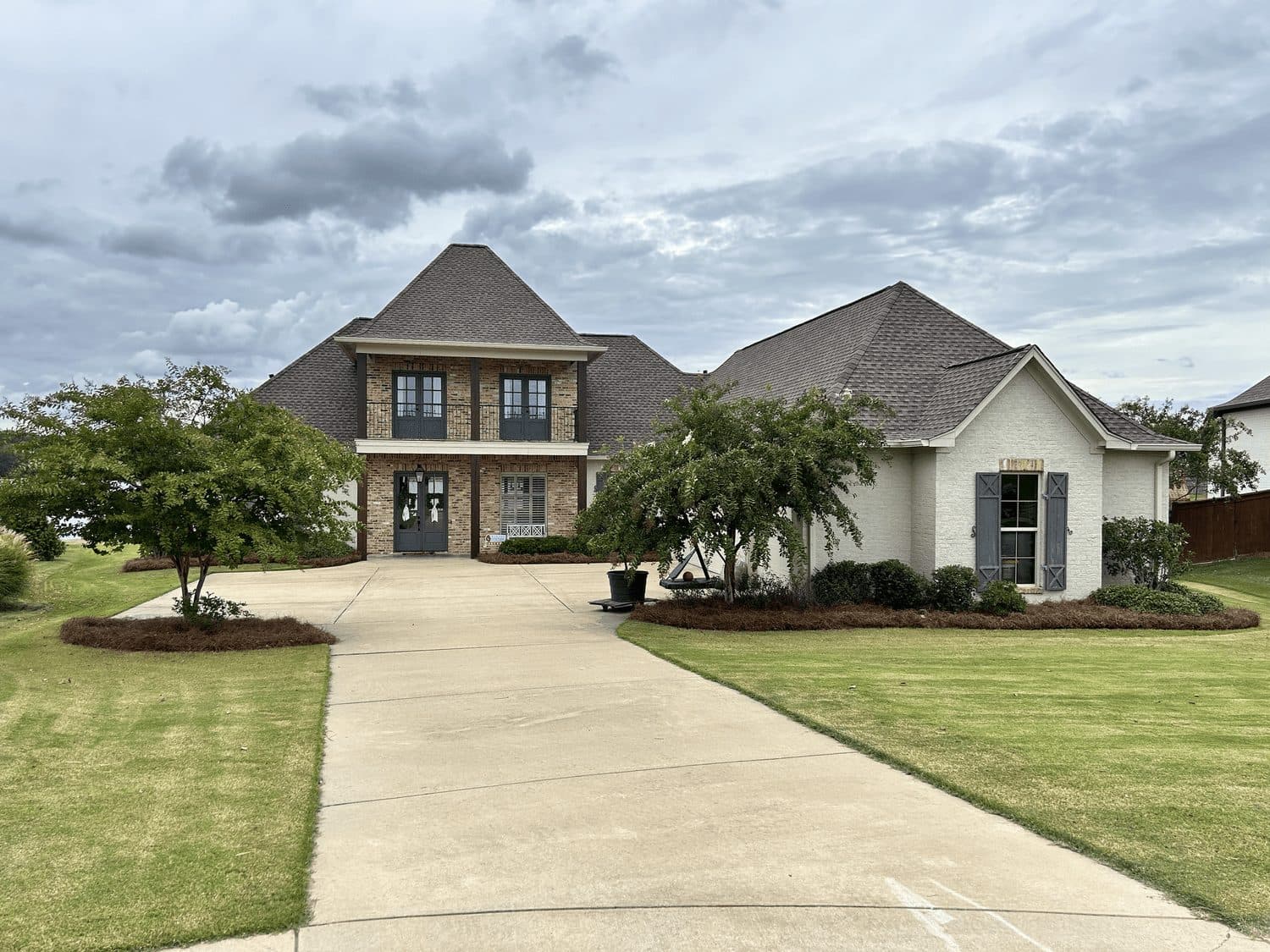Long driveway, lawn and tree rings at a two-story stone home